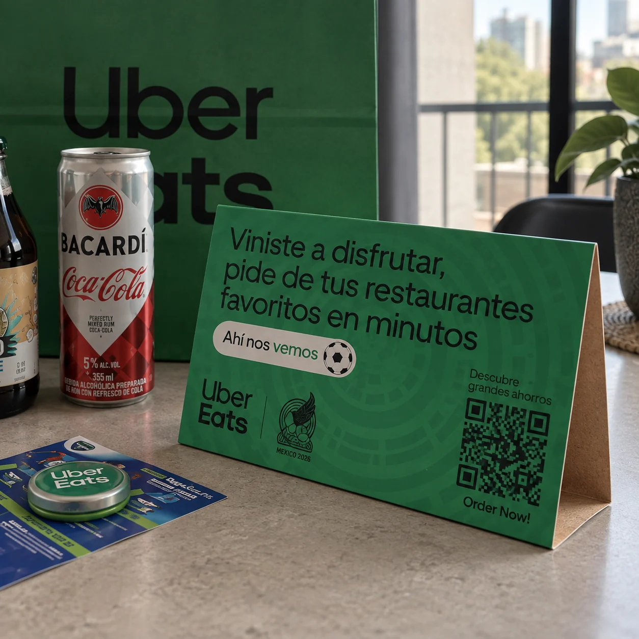 Tent card de Uber Eats en primer plano sobre la barra de la cocina, junto a las bebidas del kit
