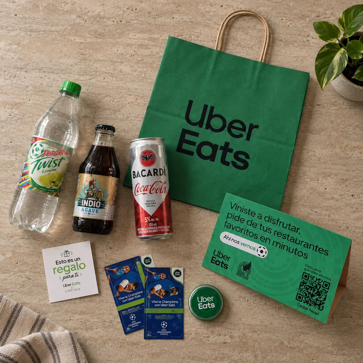 Kit de Uber Eats desplegado en plano cenital: bolsa, bebidas, tarjeta de regalo y material impreso